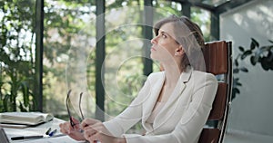 Young Caucasian business woman worker sits at the office desk, having finished her work, with pensive concentration