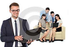 Young caucasian businessman, with his team behind holding laptop