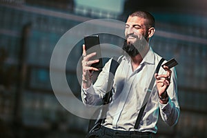 Young caucasian businessman holding a tablet and credit card outdoor