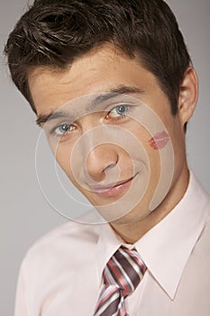 Young caucasian businessman with lipstick kiss mark on his cheek