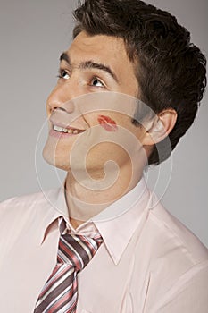 Young caucasian businessman with lipstick kiss mark on his cheek
