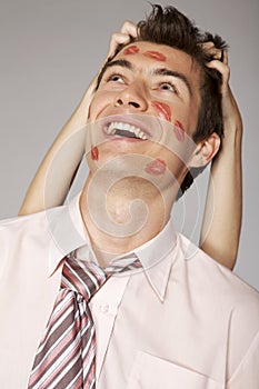 Young caucasian businessman with lipstick kiss mark on his cheek