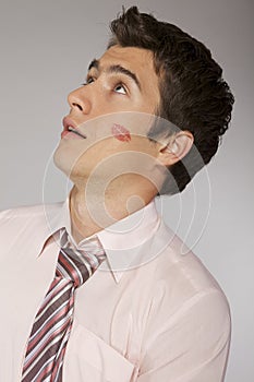 Young caucasian businessman with lipstick kiss mark on his cheek