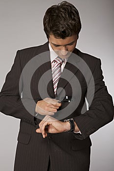 Young caucasian businessman looking on his watch with magnifying