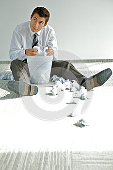 young caucasian businessman seeking document in trash bin photo