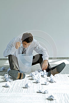 young caucasian businessman seeking document in trash bin photo