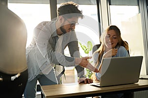 Young caucasian businessman showing something on laptop to his female colleague