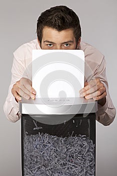 Young caucasian businessman shredding documents