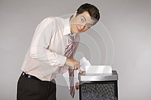 Young caucasian businessman shredding documents