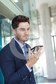 Young Caucasian businessman speaking on mobile phone while standing in modern office