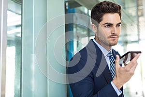 Young Caucasian businessman speaking on mobile phone while standing in modern office