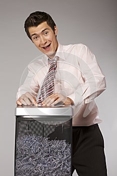 Young caucasian businessman with tie trapped in shredded machine