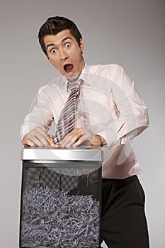 Young caucasian businessman with tie trapped in shredded machine