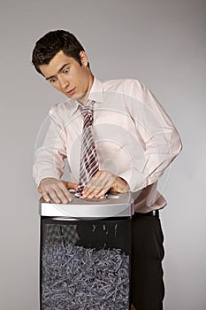 Young caucasian businessman with tie trapped in shredded machine