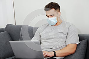 Young Caucasian businessman wearing mask prevent covid-19 virus relaxing and working with laptop in community media online in