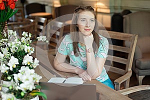 Young caucasian businesswoman in cafe sitting at the table with thoughtful stare.