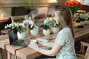 Young caucasian businesswoman in cafe sitting at the table with thoughtful stare.