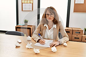 Young caucasian businesswoman frustrated writing on paperwork at the office