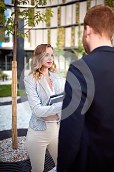 Young caucasian businesswoman looking curiously  her interlocutor outdoor in front of business building. outdoor, unofficial,