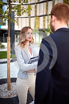 Young caucasian businesswoman looking curiously  her interlocutor outdoor in front of business building. outdoor, unofficial, photo