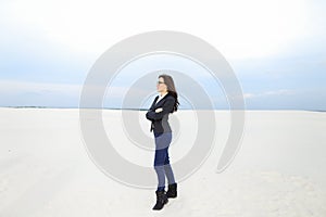 Young caucasian businesswoman standing on snow in monophonic background, wearing glasses.