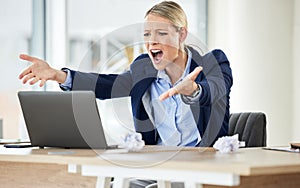 A young caucasian businesswoman yelling while using a laptop in an office at work. Female having a stressful day at work