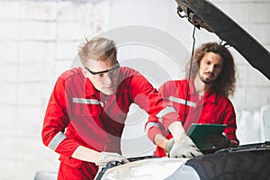 Young Caucasian car mechanic with a checklist, Mechanics in uniform are working in auto service, Technician checking modern car at