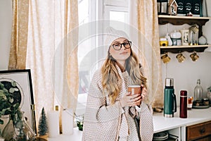 Young caucasian cheerful woman standing on a kitchen and drinking tea on winter morning