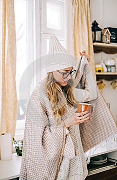 Young caucasian cheerful woman standing on a kitchen and drinking tea on winter morning