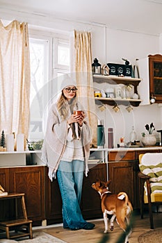 Young caucasian cheerful woman standing on a kitchen and drinking tea on winter morning