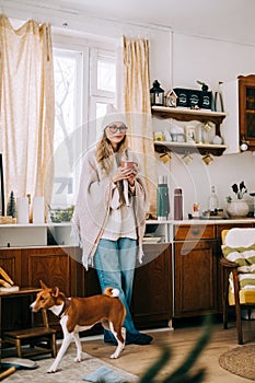 Young caucasian cheerful woman standing on a kitchen and drinking tea on winter morning