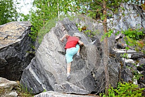 Young caucasian child boy climbing rocks in forest