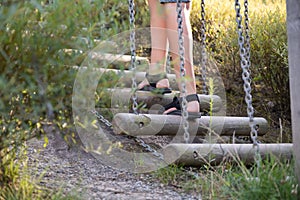 Young caucasian child playing on playground, climbing a wooden ladder in rope park.