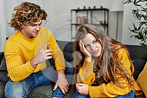 Young caucasian couple arguing sitting on sofa at home