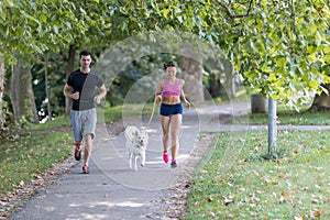 Young caucasian couple with dog running in park, couple jogging together