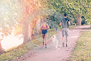 Young caucasian couple with dog running in park, couple jogging together