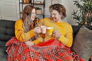 Young caucasian couple drinking coffee hugging each other at home