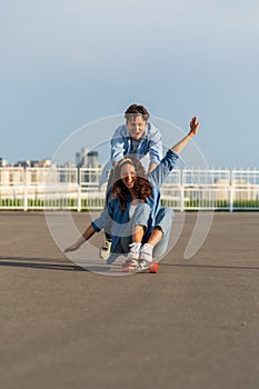 Young couple enjoy skateboarding together on street. Hipster man push back of woman sit on longboard