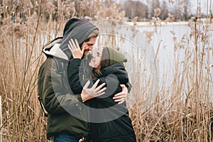 A young Caucasian couple in love is standing in an embrace near a lake and reeds. Weekends and walks in nature. Outdoor recreation