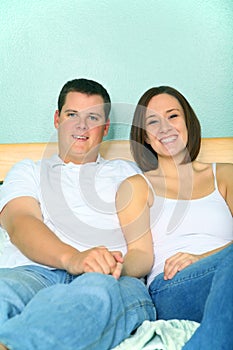 Young Caucasian Couple Sitting On Bed