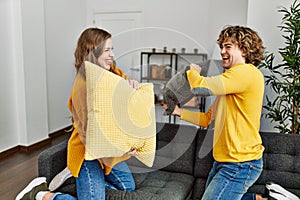 Young caucasian couple smiling confident figthing with pillow at home