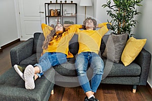 Young caucasian couple smiling confident relaxed with hands on head at home