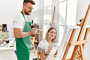 Young caucasian couple smiling happy drawing at art studio