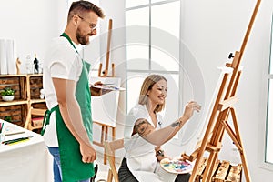 Young caucasian couple smiling happy drawing at art studio