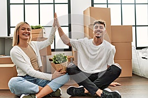 Young caucasian couple smiling happy high five sitting at new home