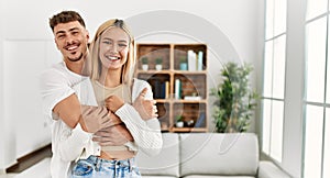 Young caucasian couple smiling happy and hugging standing at home