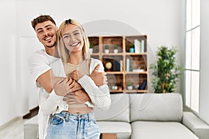 Young caucasian couple smiling happy and hugging standing at home