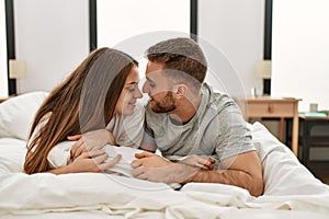 Young caucasian couple smiling happy and kissing on the bed at home