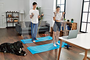 Young caucasian couple smiling happy training power with elastic band at home