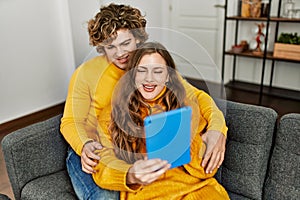 Young caucasian couple using touchpad hugging each other at home